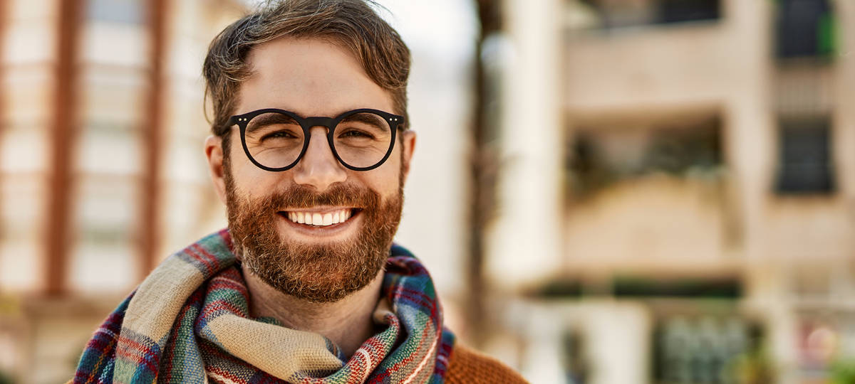 Young man with beard wearing glasses outdoors on a sunny day